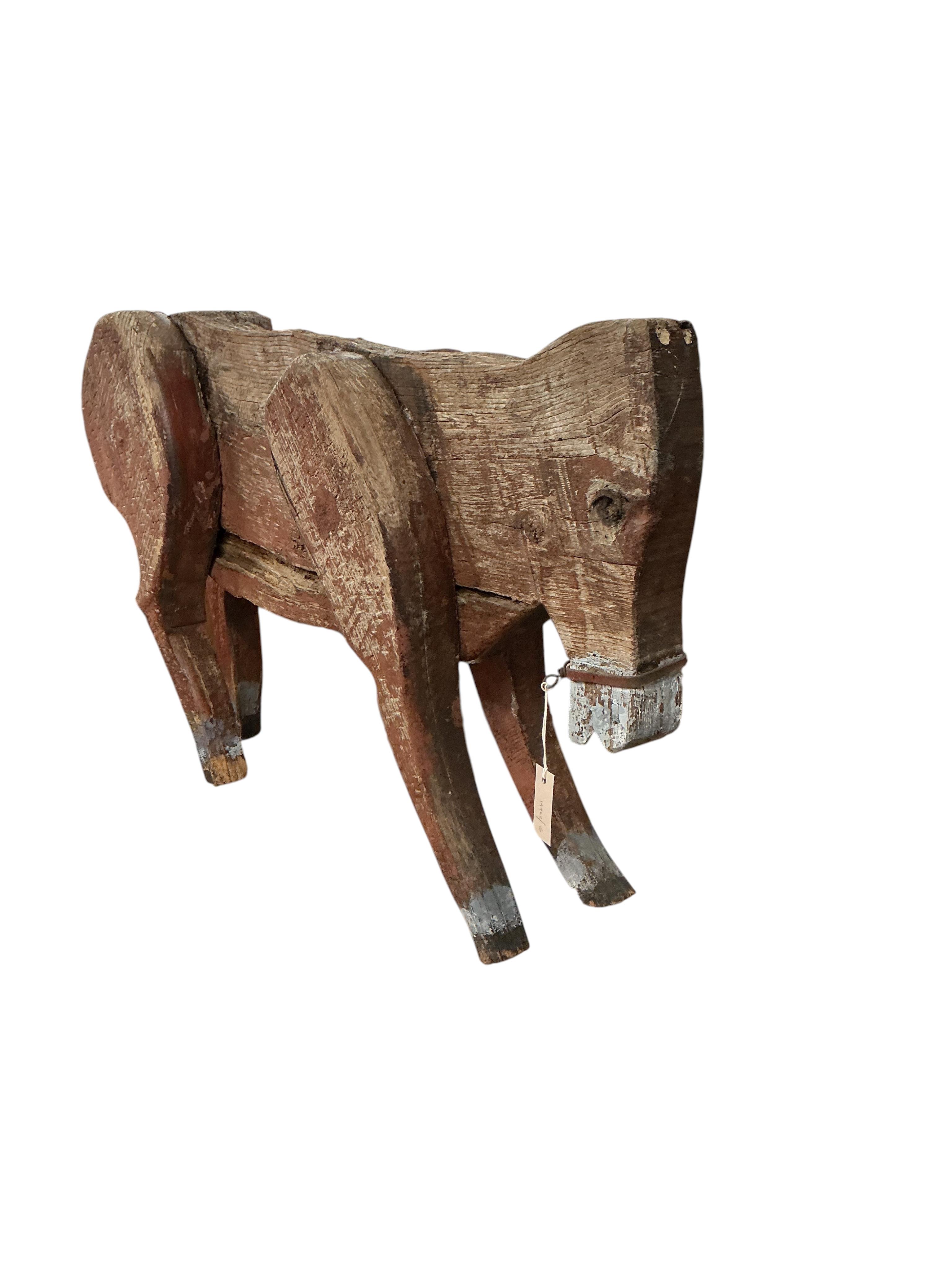 A 19th century primitive painted wood model of a cow with articulated limbs, length 100cm, height 62cm